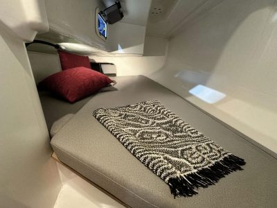 Bootkabine: Bett, graue Matratze, rote Kissen, Zebra-Decke, Fenster