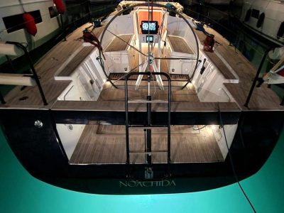 Segelboot im Trockendock, Cockpit mit Steuerrad, Holzdeck und Innenraum sichtbar.