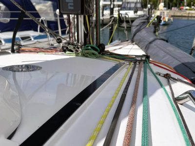 Segelbootdeck mit bunten Leinen (gelb, grün, braun) am Kai, Marina im Hintergrund